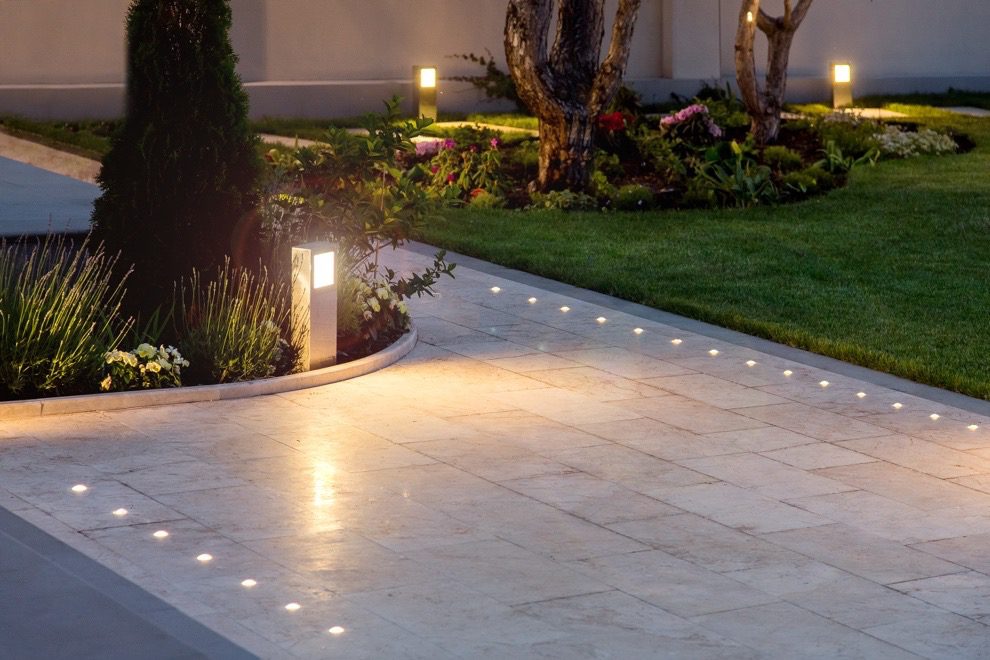 Commercial landscape lighting illuminating walkway, turf, and planting beds at night